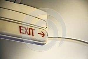 Close up of emergency door exit sign with red arrow on the ceiling of the airplane, copy space