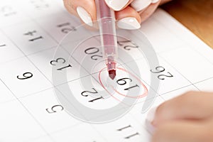 Close up on employee woman hand using red pen to writing schedule on 19th day of the monthcalendar 2022 to make an appointment