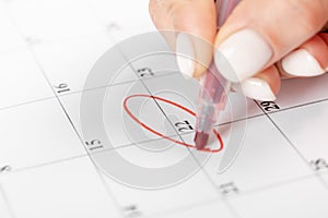 Close up on employee woman hand using red pen to writing schedule on 22 day calendar 2022 to make an appointment meeting or manage