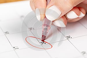 Close up on employee woman hand using red pen to writing schedule on 24 day calendar 2022 to make an appointment meeting or manage