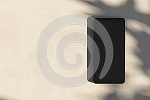 Close up of empty cellphone on light surface with leaf shadows. Presentation concept. Mock up