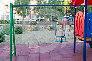 Close-up of empty colorful plastic baby swing on Playground in Park on summer day