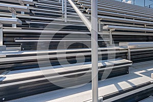 Close-Up of empty metal stadium bleacher seats along aisle with steps and railing.