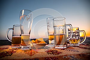 Close up empty mugs of beer on a sunrise background with mountains. Beer party is over concept.