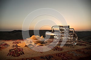 Close up empty mugs of beer on a sunrise background with mountains. Beer party is over concept.