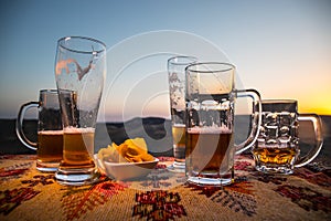 Close up empty mugs of beer on a sunrise background with mountains. Beer party is over concept.