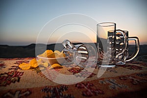 Close up empty mugs of beer on a sunrise background with mountains. Beer party is over concept.