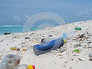 CLOSE UP: Empty plastic bottles are flooded onto the tropical white sand beach.