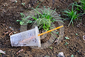 Close up of empty plastic cup on the grass ground. Plastic waste pollution concept