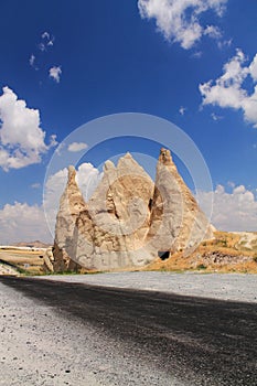 Close up on empty road with stunning troglodytes rising up in blue sky, cappadocia, turkey