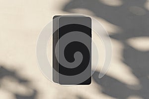 Close up of empty smartphone on light surface with leaf shadows. Presentation concept. Mock up