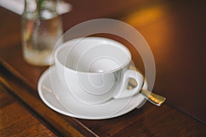 Close-up empty white cup with saucer and spoon on a table