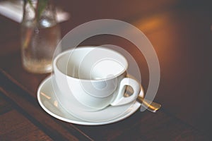 Close-up empty white cup with saucer and spoon on a table