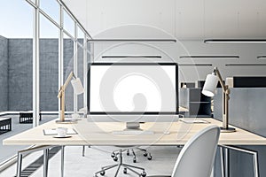 Close up of empty white mock up computer monitor on wooden office desktop in modern interior. Workplace concept.