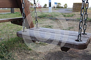 Close-up of an empty wooden swing in the playground