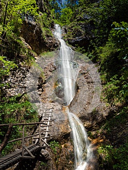 CLOSE UP: Empty wooden trail and ladder lead up to a crystal clear waterfall.