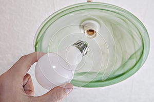 Close-up of energy-saving LED light bulb in human hand.