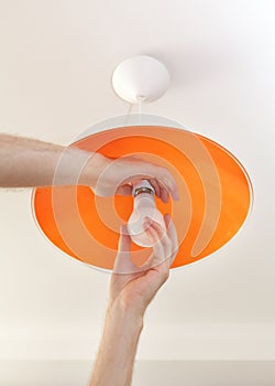 Close-up of energy-saving LED light bulb in the human hand, the replacement of the lamp in the ceiling luminaire