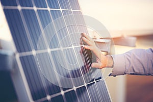 Close up of engineer hand is checking an operation of sun and cleanliness of photovoltaic solar panels on a sunset. Concept: