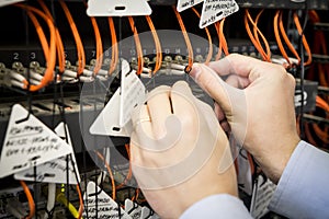 Close-up of engineer`s hand with optical patch cord is connected to switch. Setting up data center equipment