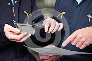 Close Up Of Engineers Measuring Component With Micrometer