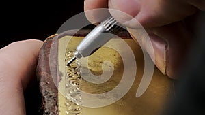 Close-up of engravers hands engraving on gold watch blank, handmade watch production order, watch custom order