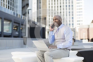 Close-up of enterprising black man working with his laptop on the street