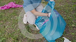 Close-up of environmental aware girl picking up plastic into trash bag