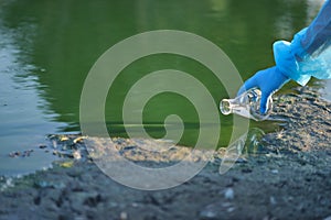 Close-up environmentalist hand of a researcher in a process of taking a sample of contaminated water from a lake