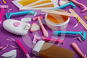 Close-up of epilator, disposable razor, wax, wax strips, on a pink background.