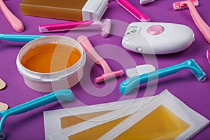 Close-up of epilator, disposable razor, wax, wax strips, on a pink background.