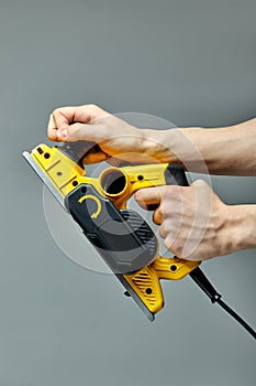 close-up equipment carpenter maker hand tools on electric planer for processing wooden door isolate on gray