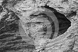 Close up of eroded hole in cliff rock texture background in black and white