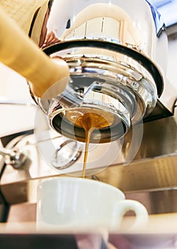 Close-up of espresso pouring from coffee machine with bottomless portafilter. `Tiger striping`