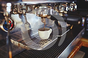 Close-up of espresso pouring from coffee machine.Espresso cup from coffee machine make by barista in shop cafe