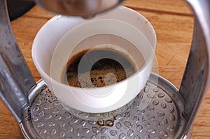 Close-up of espresso pouring from coffee machine. Man hand with coffee