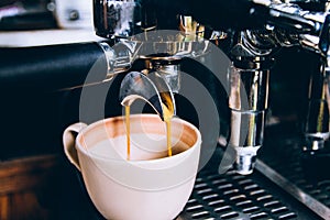 Close-up, Espresso pouring from making fresh coffee machine. Professional coffee shop. Vintage color tone