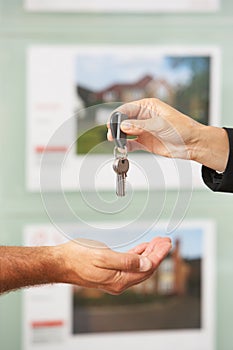 Close Up Of Estate Handing Over Keys Of New Home