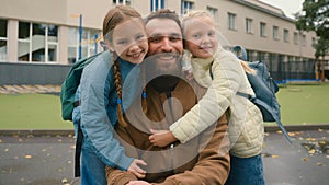 Close up European man little girls father and daughters hug sisters together happy family smiling schoolgirls children