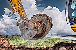 Close up of excavator bucket at construction site. The excavator is digging a trench for underground utilities. Construction