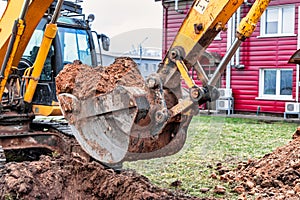 Close up of excavator bucket at construction site. The excavator is digging a trench for underground utilities. Construction