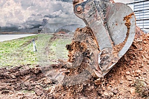 Close up of excavator bucket at construction site. The excavator is digging a trench for underground utilities. Construction