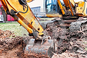 Close up of excavator bucket at construction site. The excavator is digging a trench for underground utilities. Construction