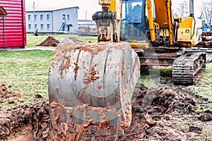 Close up of excavator bucket at construction site. The excavator is digging a trench for underground utilities. Construction