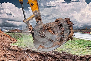 Close up of excavator bucket at construction site. The excavator is digging a trench for underground utilities. Construction