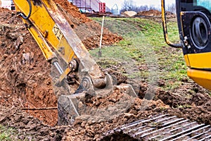 Close up of excavator bucket at construction site. The excavator is digging a trench for underground utilities. Construction