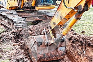 Close up of excavator bucket at construction site. The excavator is digging a trench for underground utilities. Construction