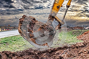 Close up of excavator bucket at construction site. The excavator is digging a trench for underground utilities. Construction