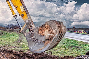 Close up of excavator bucket at construction site. The excavator is digging a trench for underground utilities. Construction