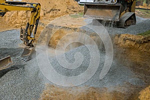 Close up excavator working on a construction site, excavator bucket levels gravel on the building foundation